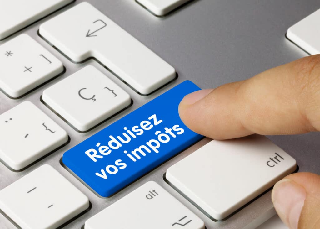 Réduisez vos impôts : l'astuce sur votre clavier. Doigt pressant une touche bleue de clavier affichant le texte blanc "Réduisez vos impôts".